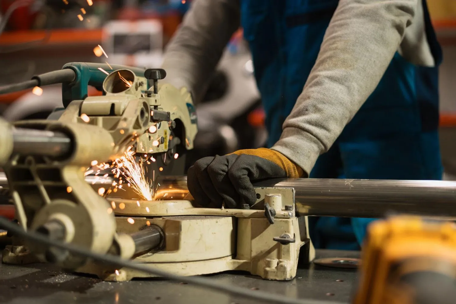 Worker using a circular grinder on metal, throwing sparks